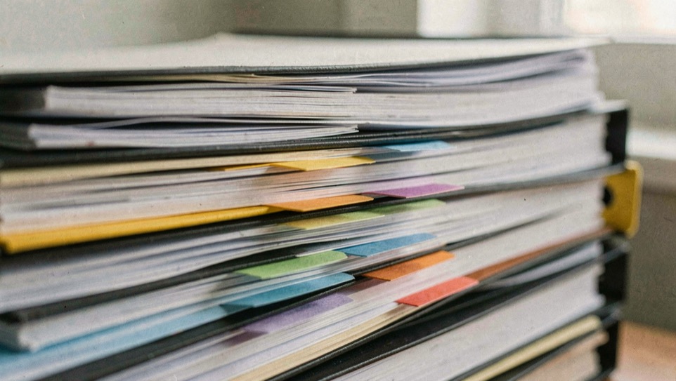 A stack of technical binders seen edge on, paper tabs of several colors marking pages deep inside the middle volume